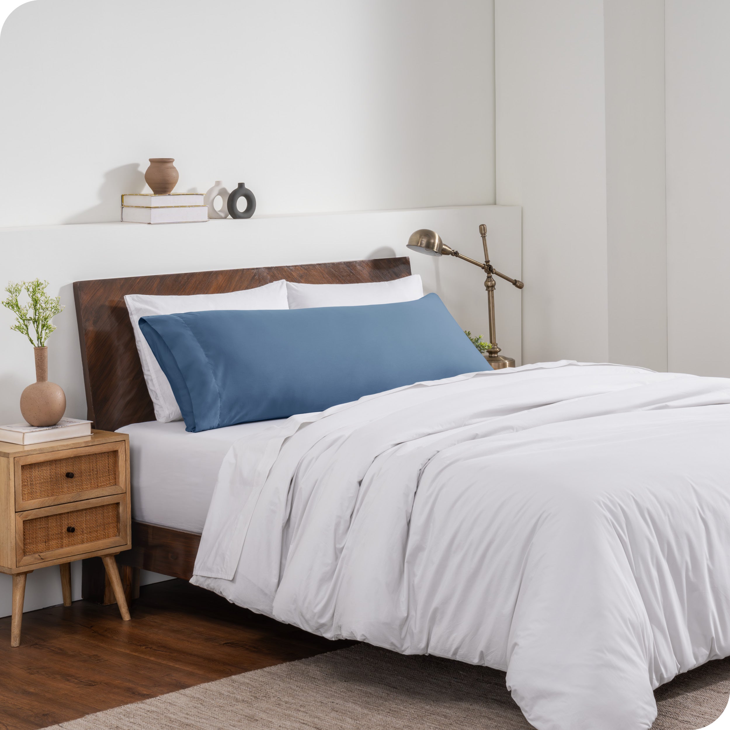 A body pillow cover on a pillow on a bed made with all white bedding