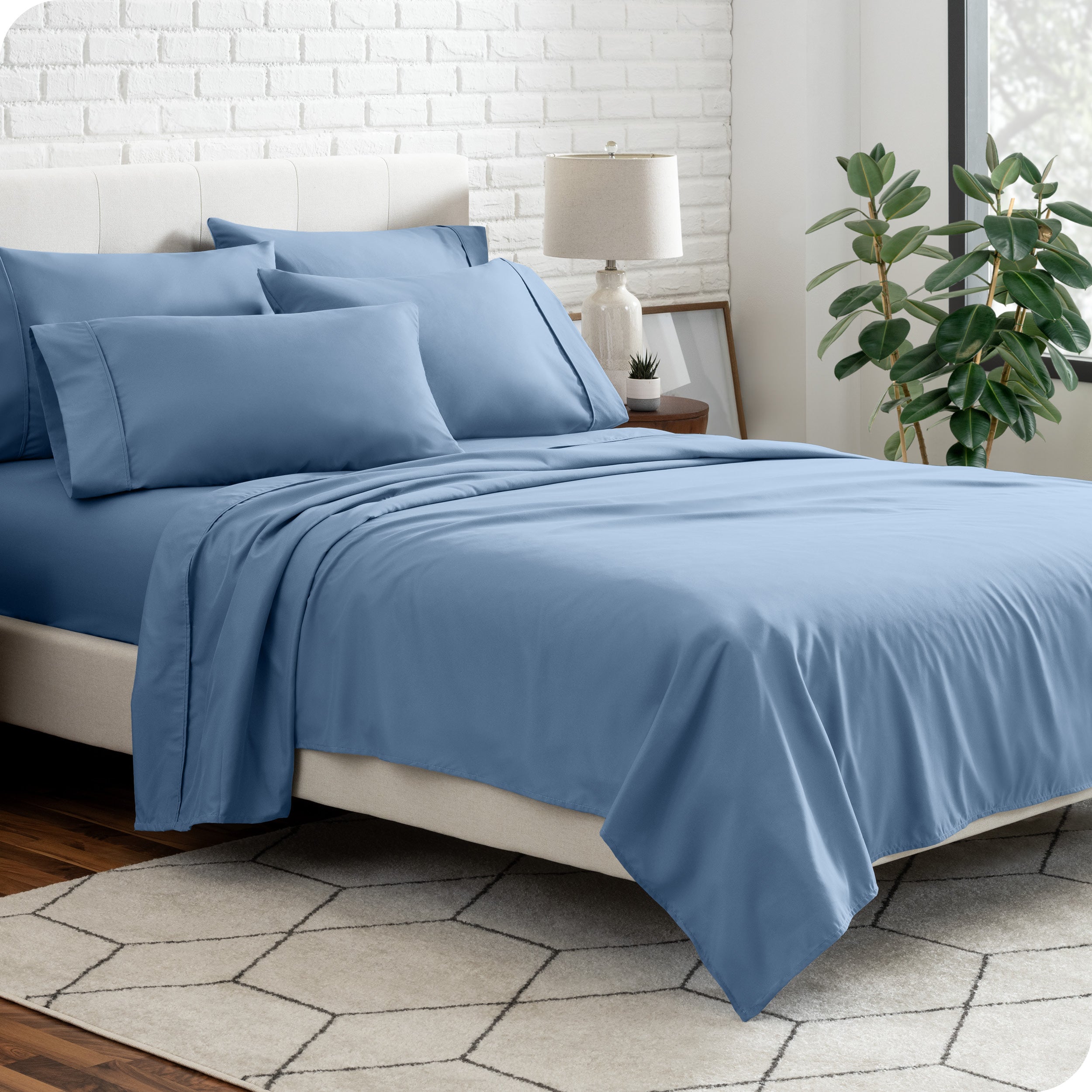 A bedroom setting with a bed made with the microfiber bed sheets and four pillows.