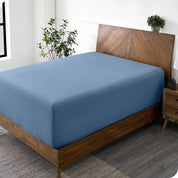 A wide corner view of a modern bed made with a microfiber fitted sheet on the mattress. 