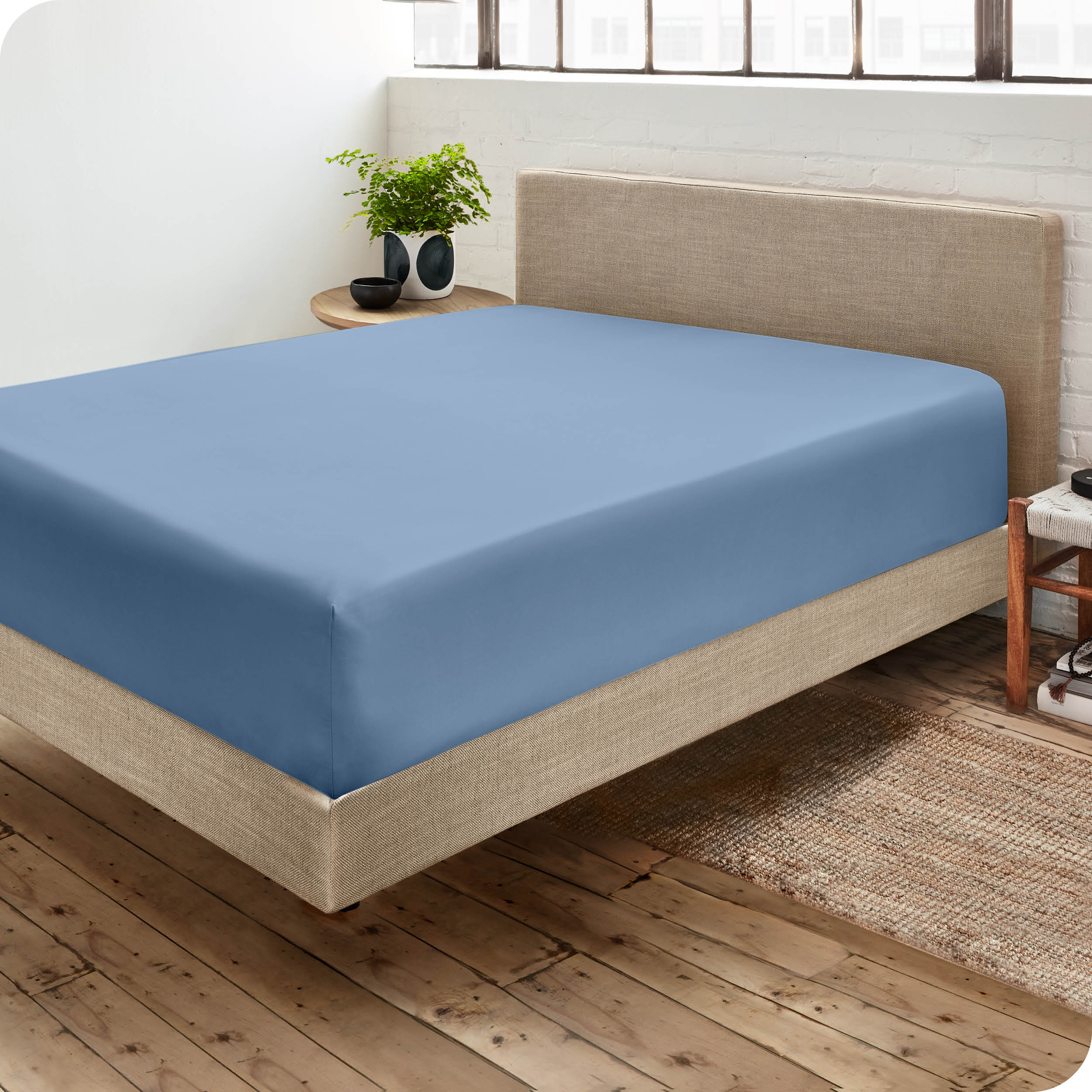 Corner view of a modern bed with a microfiber fitted sheet on the mattress. 