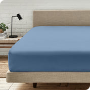 A bed with a microfiber fitted sheet on the mattress. 