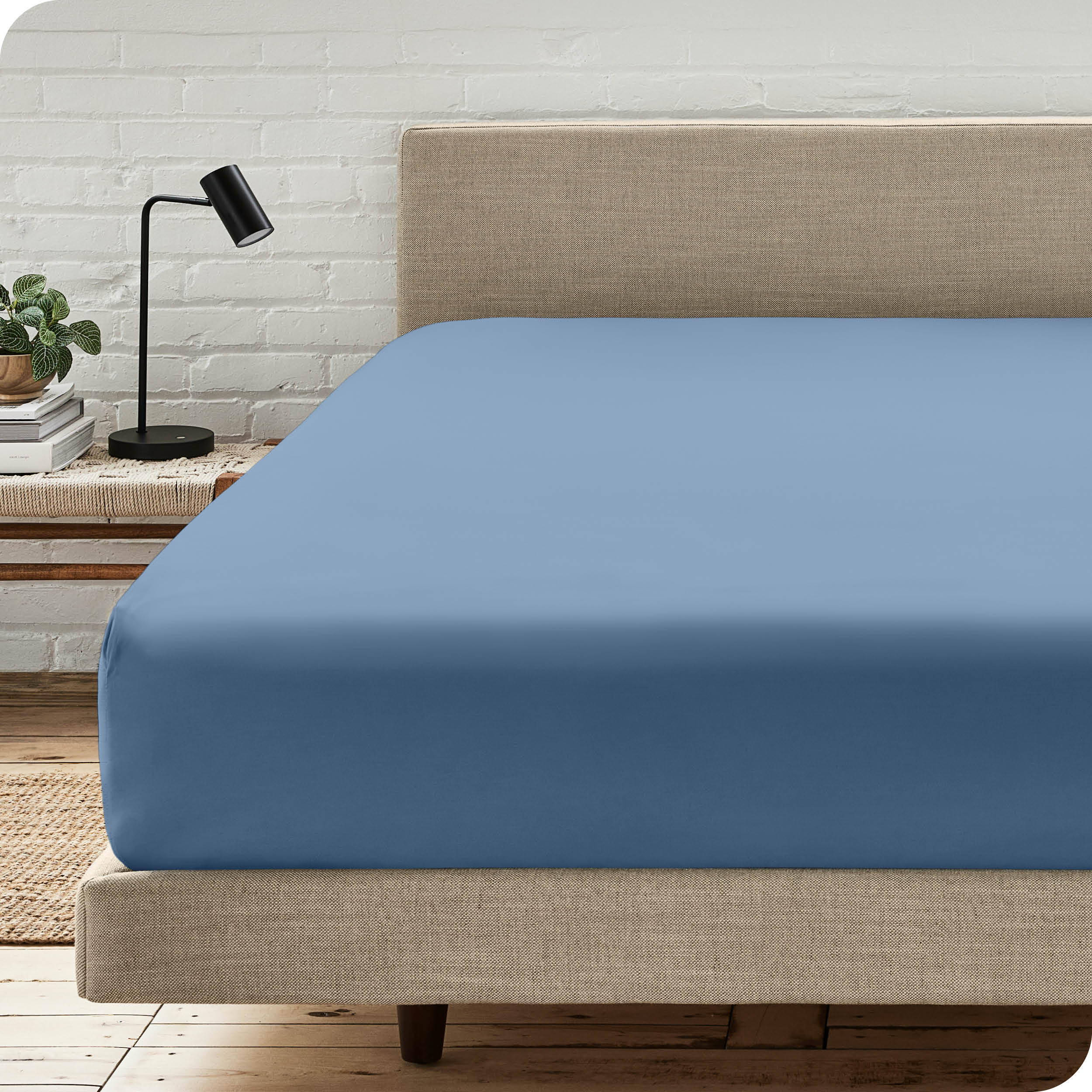 A bed with a microfiber fitted sheet on the mattress. 