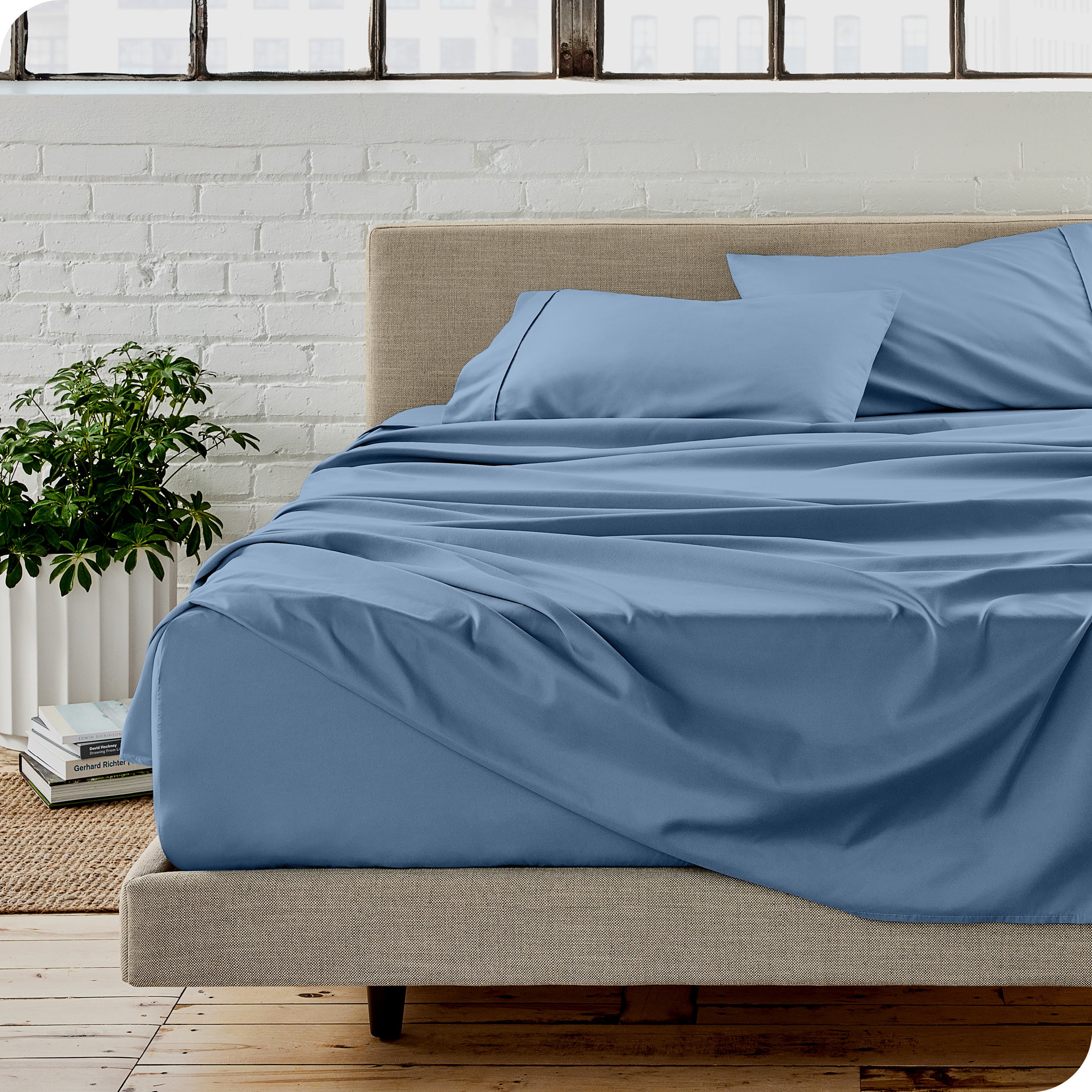 Microfiber sheets on a bed with a brick wall behind it