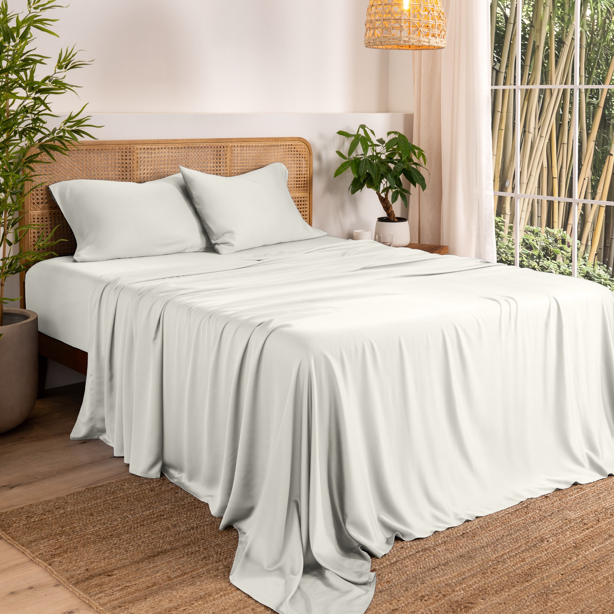 Bamboo sheets on a bed in a bedroom with plants and a window.