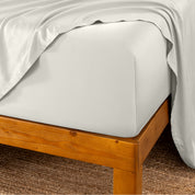 Bed sheets on a wooden bed frame with a brown carpet background