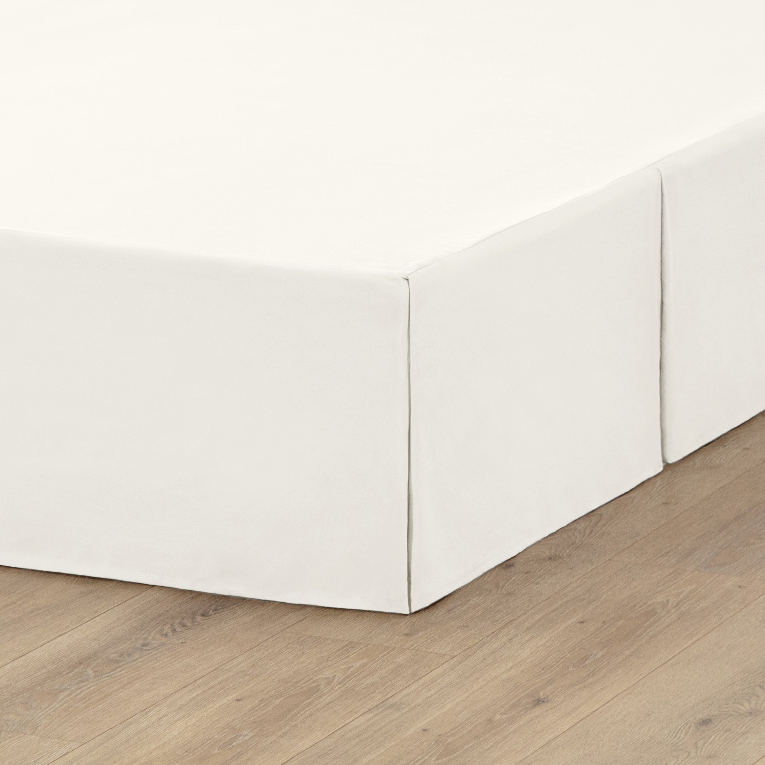 A box spring with a bed skirt on it