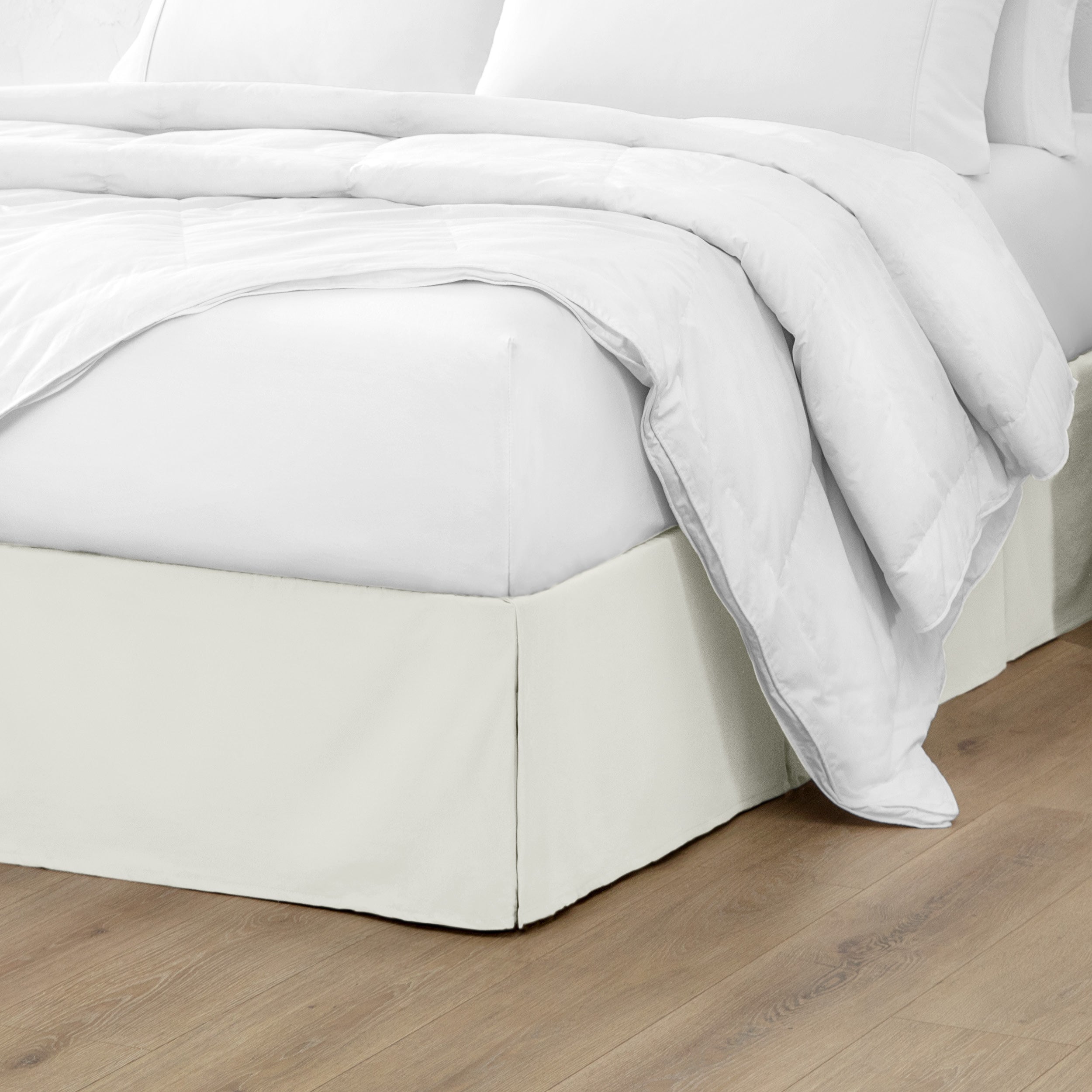 The corner of a bed with a bed skirt and comforter on it