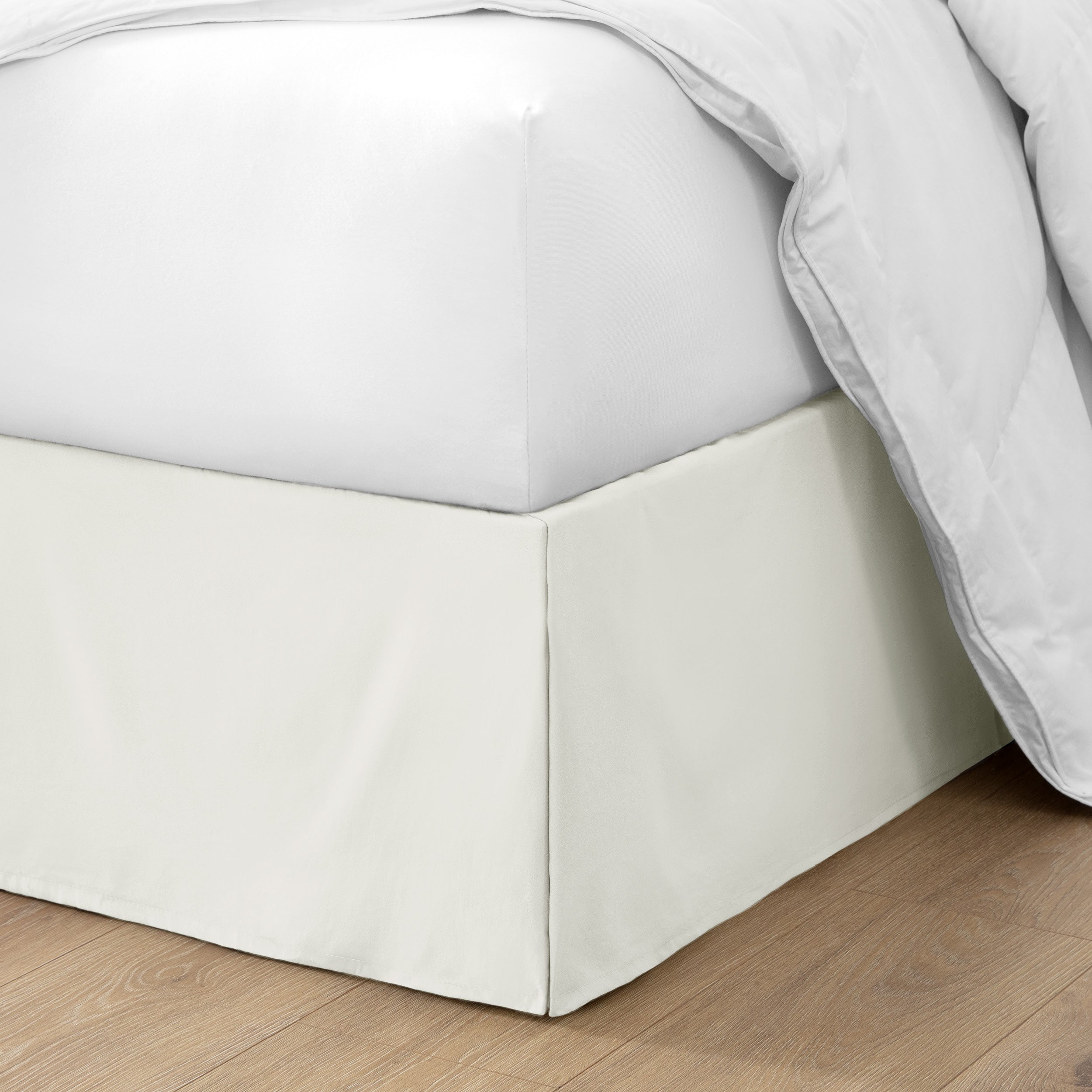 The corner of a bed with a bed skirt and comforter on it