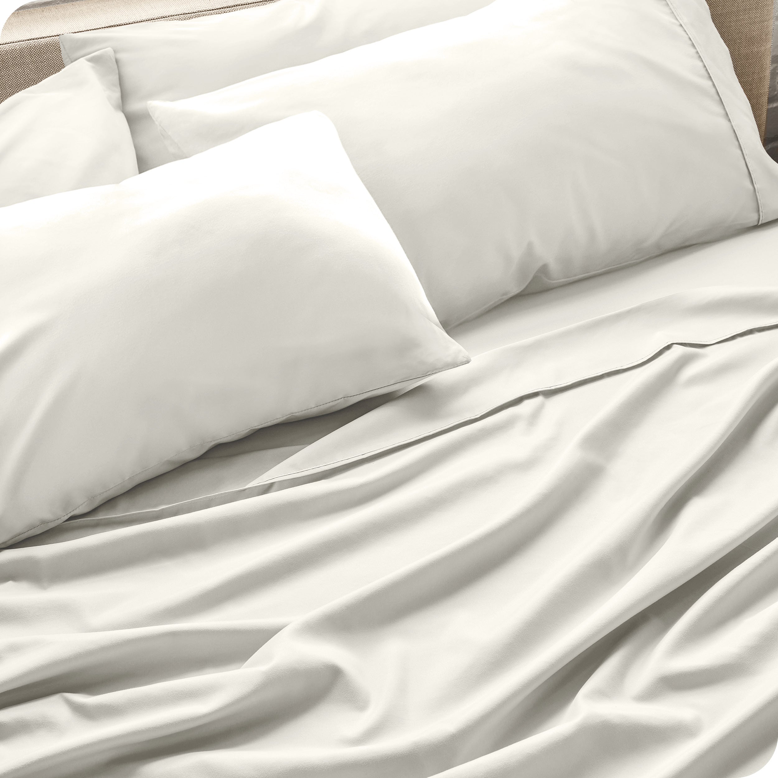 Close up of the microfiber bed sheets on a bed with four pillows.
