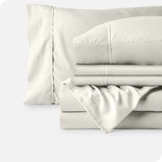 Microfiber sheets neatly folded with corner draped over, two folded pillowcases and two display pillows.