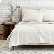 End view of a modern bed with the microfiber sheets on the bed with four pillows.