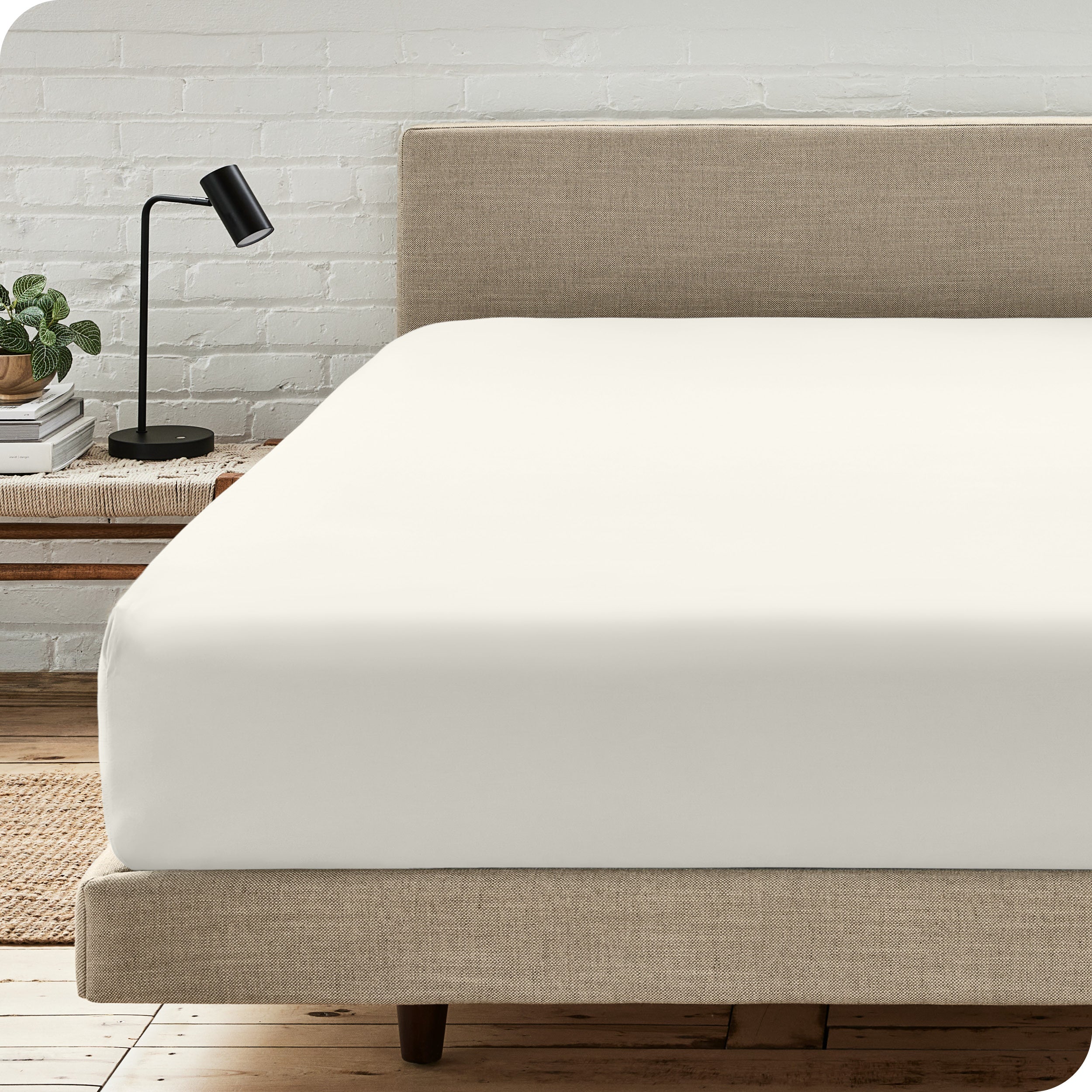 A bed with a microfiber fitted sheet on the mattress. 
