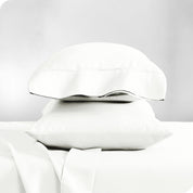 Two pillowcases on pillows stacked on a bed with matching sheets