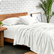 Microfiber sheets and matching pillowcases on a bed next to a large plant