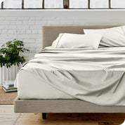 Microfiber sheets on a bed with a brick wall behind it