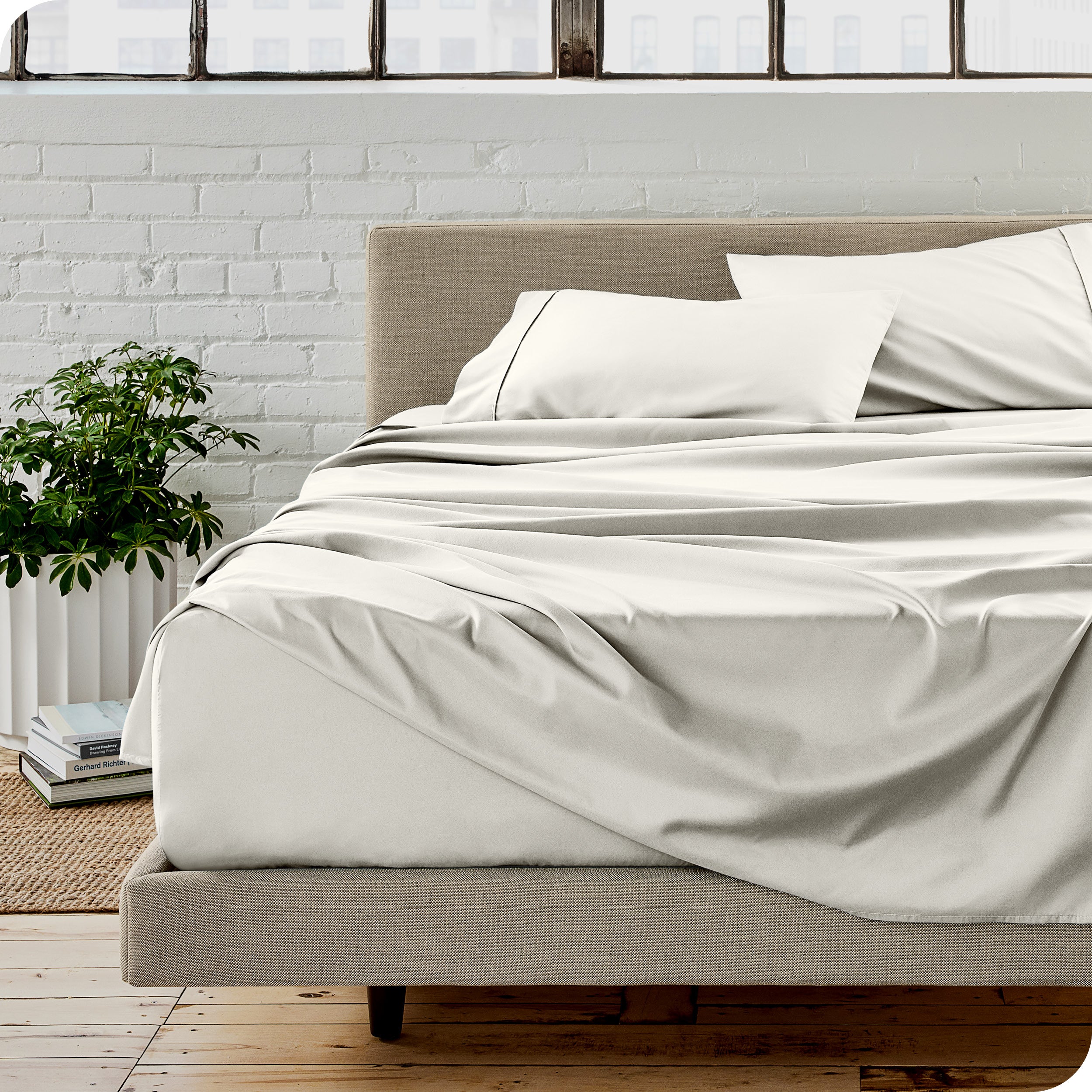 Microfiber sheets on a bed with a brick wall behind it