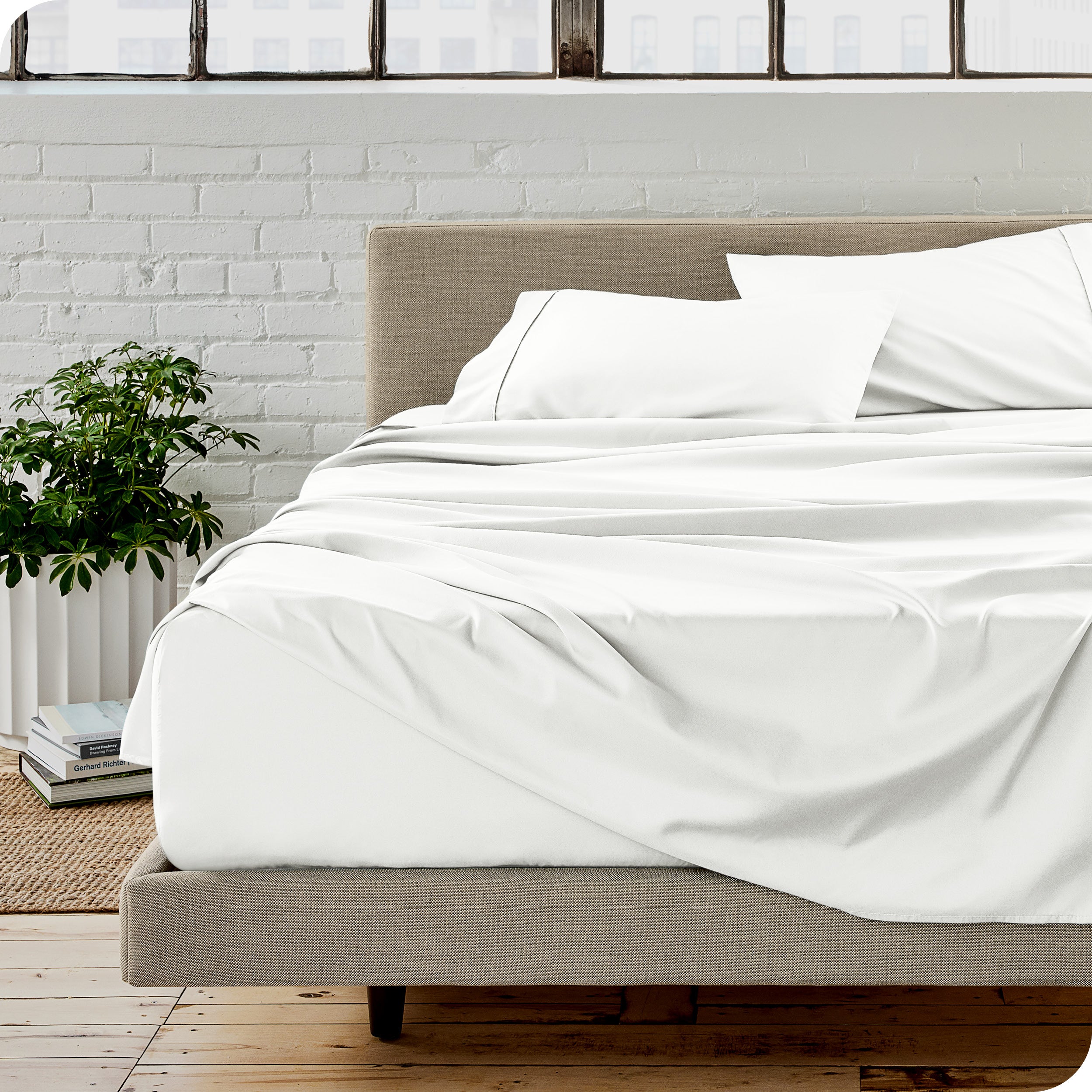 Microfiber sheets on a bed with a brick wall behind it