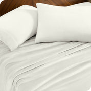 Two pillows with pillowcases on them set on a bed with matching sheets