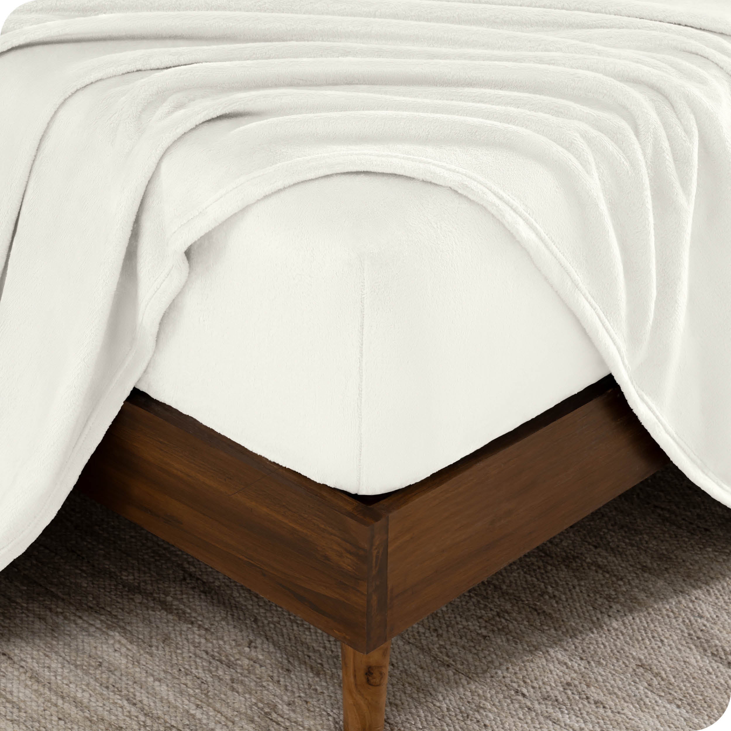 A corner of a mattress with a fitted sheet and a flat sheet on it.