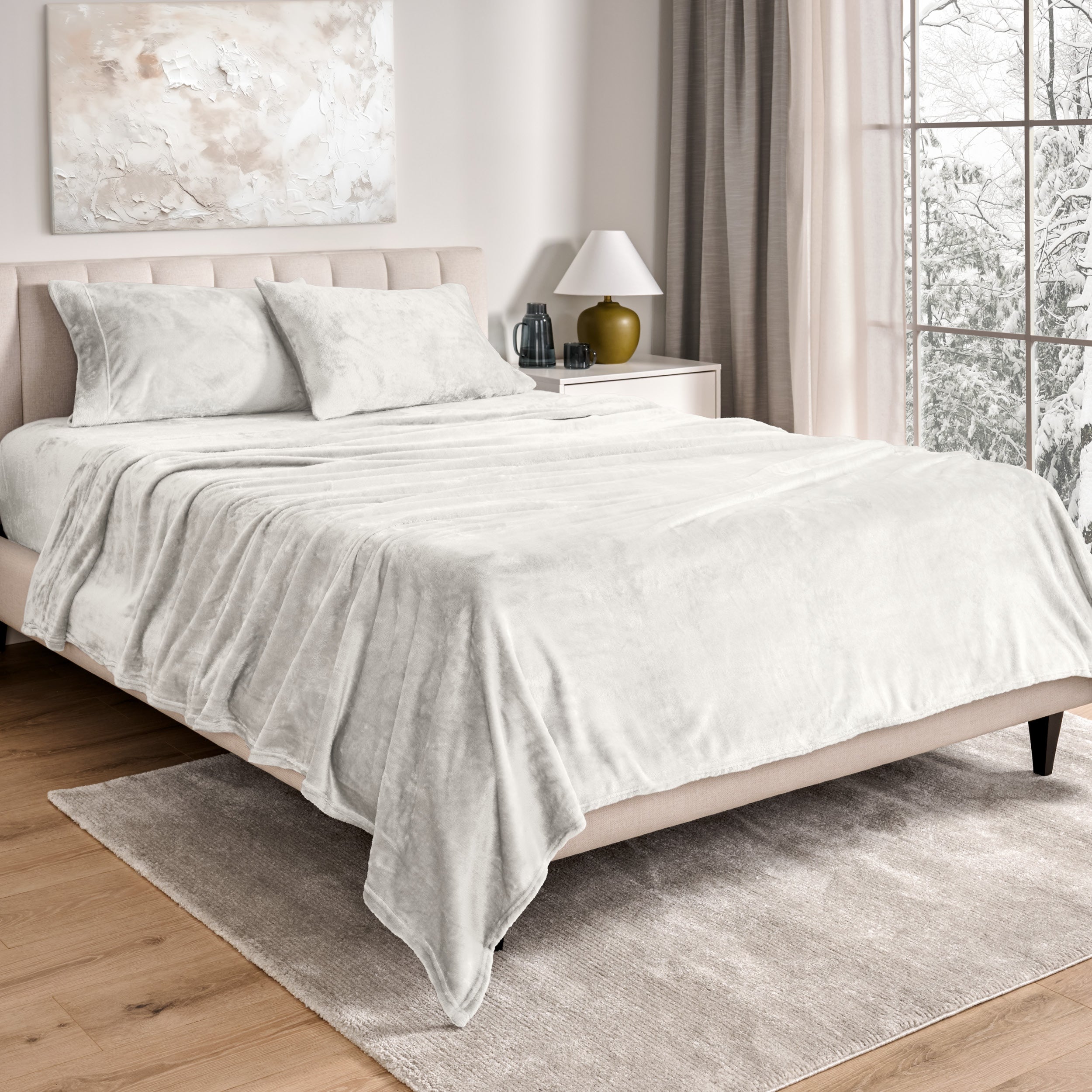 Sheets and matching pillowcases on a bed in a bedroom with a lamp and window in the background.