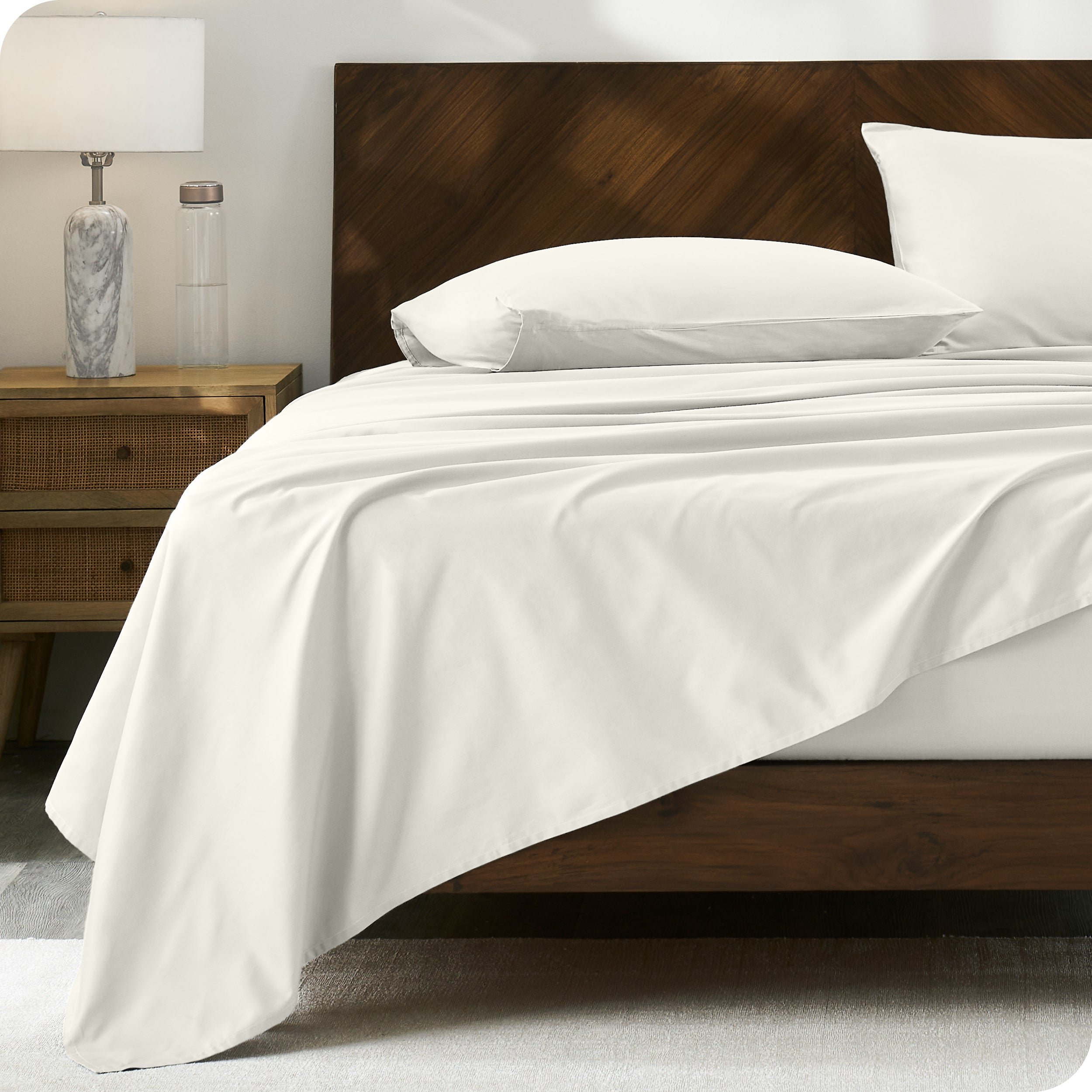 Percale sheet set on a bed with a wooden headboard
