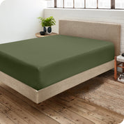 Corner view of a modern bed with a microfiber fitted sheet on the mattress. 