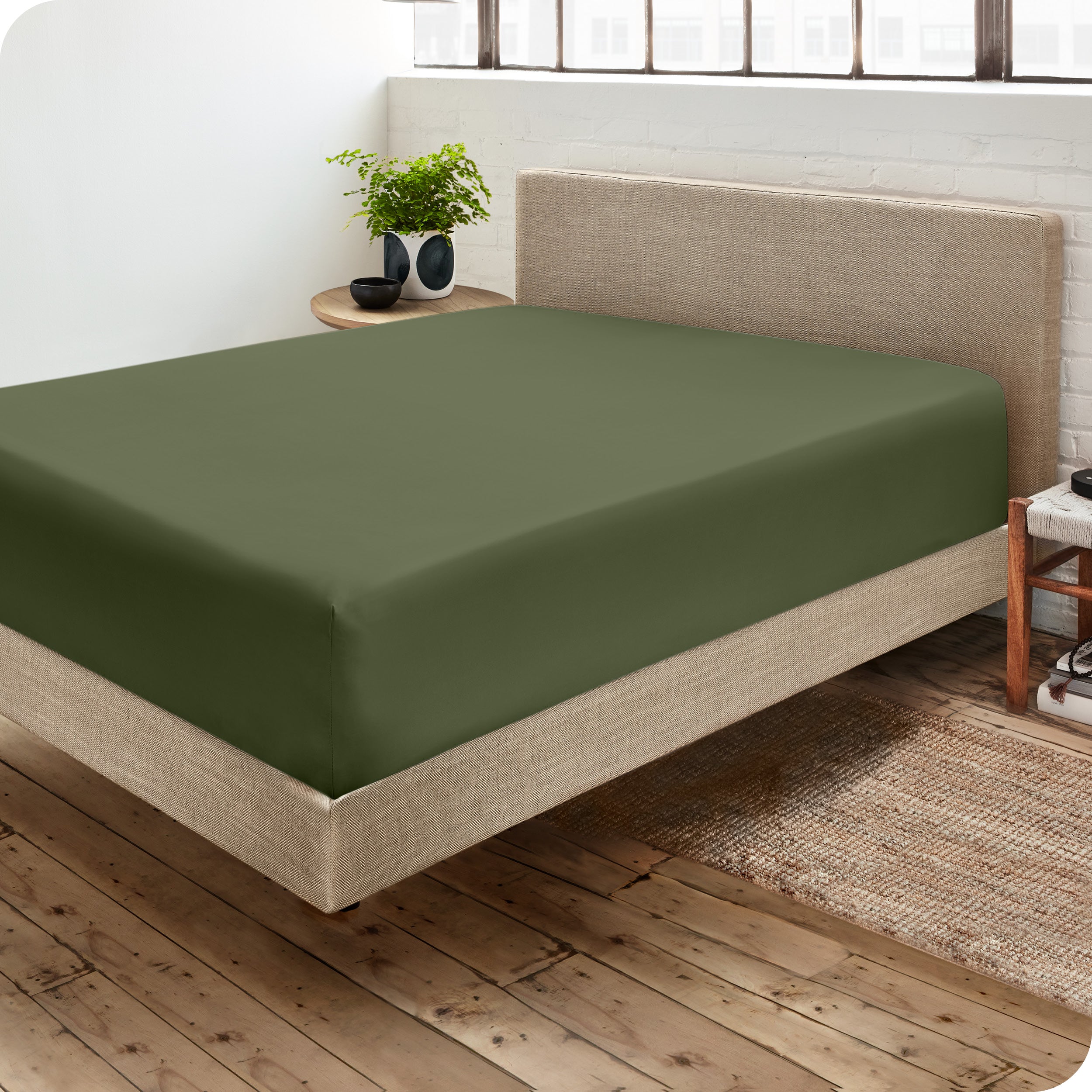 Corner view of a modern bed with a microfiber fitted sheet on the mattress. 