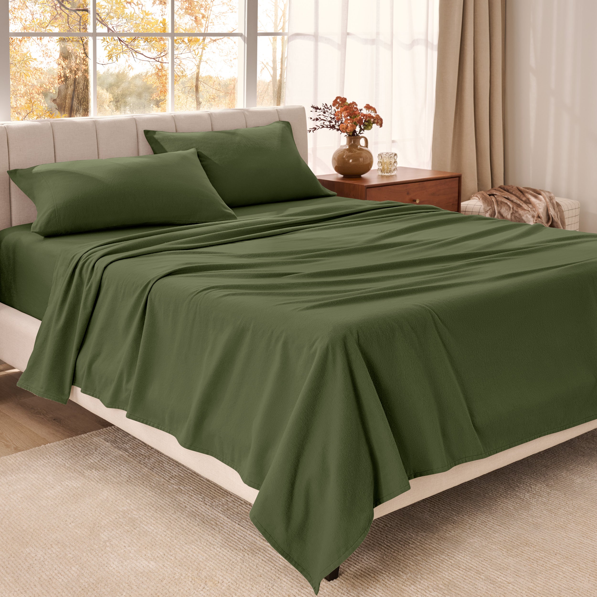 Organic flannel bed sheets on a neatly made bed in a bright bedroom with large windows.