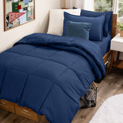 A college dorm room with a bed in a bag set on the mattress
