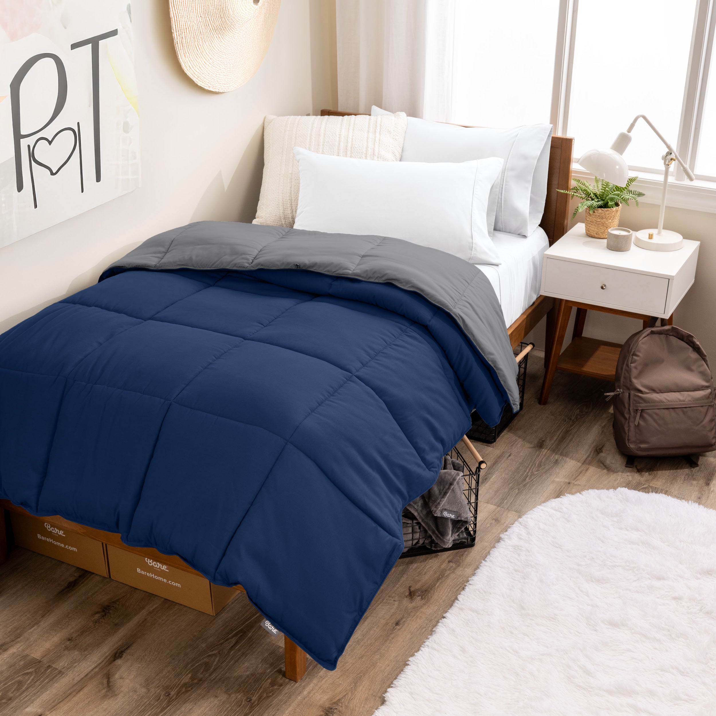 Wooden bed frame with a reversible comforter on the bed. The comforter is folded back over showing the two different colors.