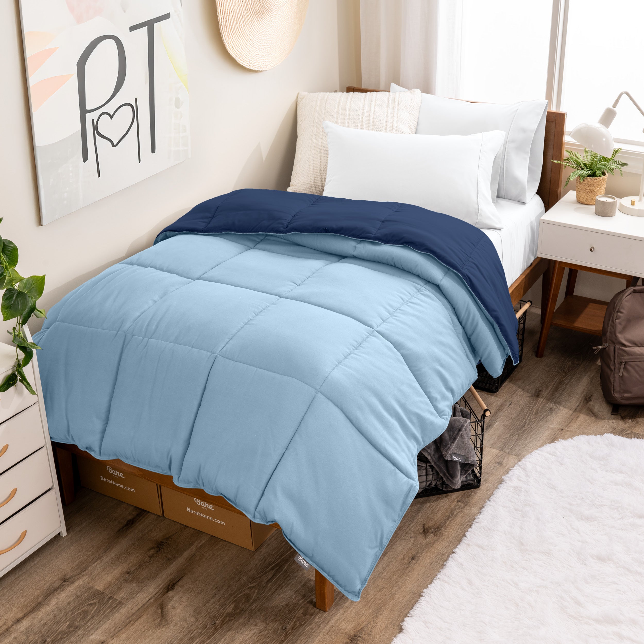 Wooden bed frame with a reversible comforter on the bed. The comforter is folded back over showing the two different colors.
