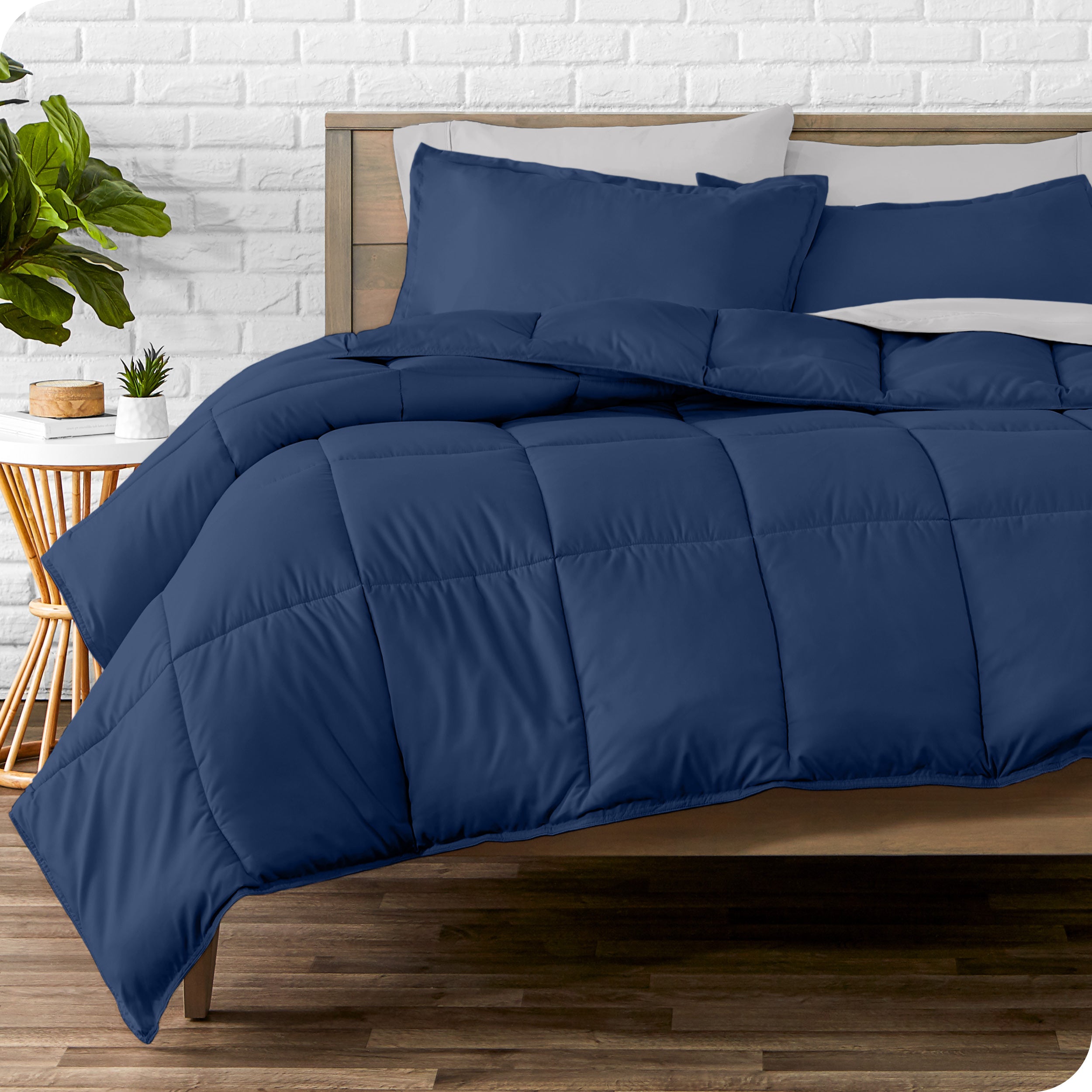 A wooden bed frame with sheets, pillow shams and a comforter on the bed