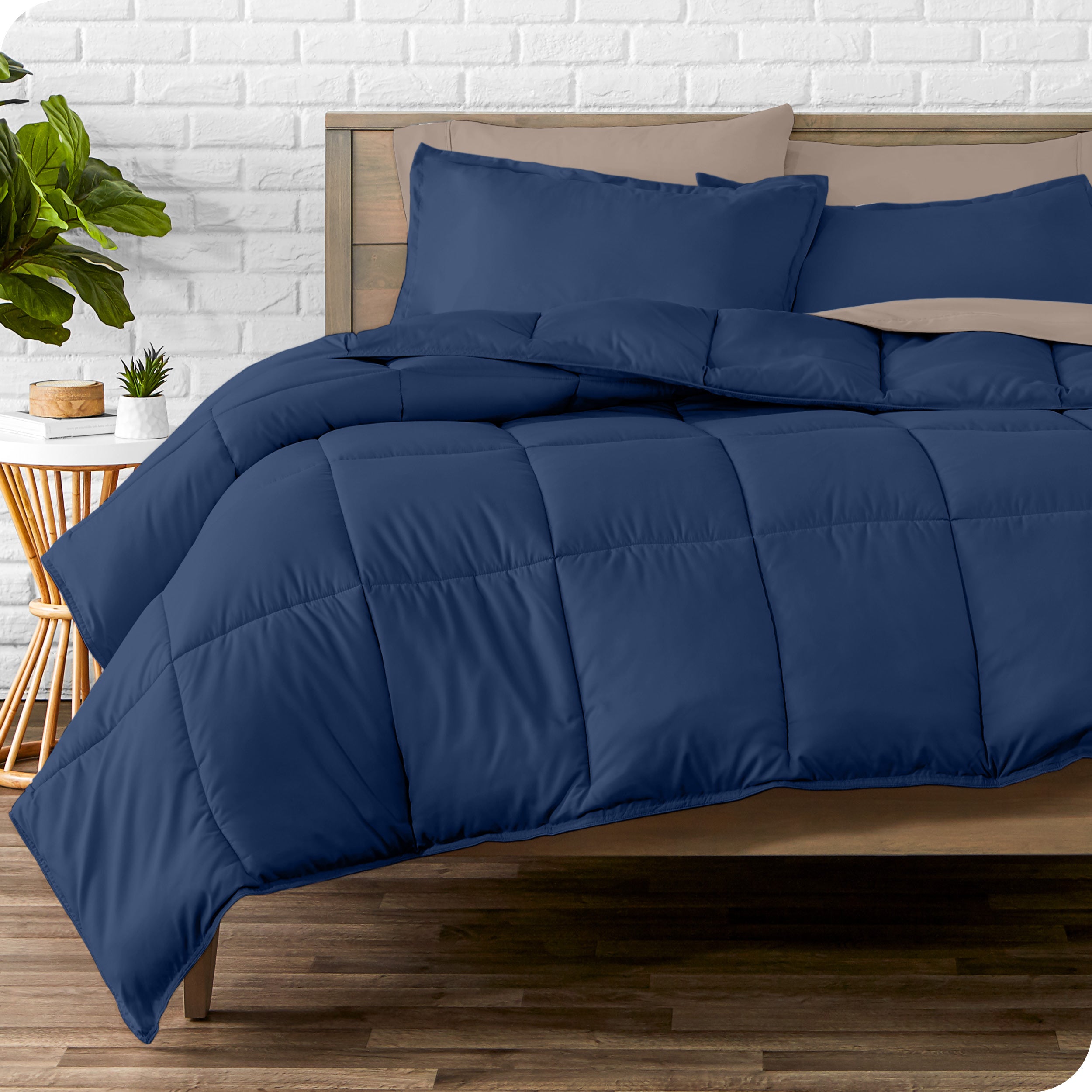 A wooden bed frame with sheets, pillow shams and a comforter on the bed