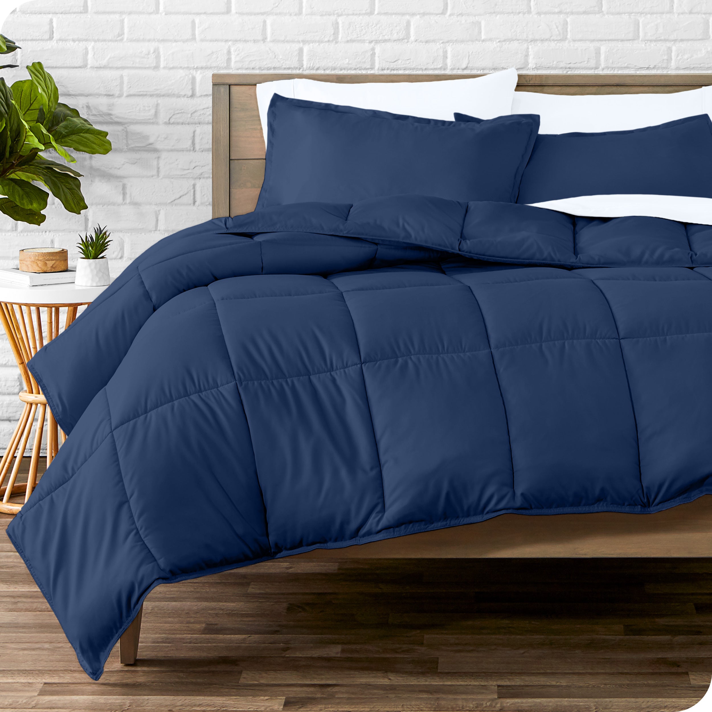 A wooden bed frame with sheets, pillow shams and a comforter on the bed