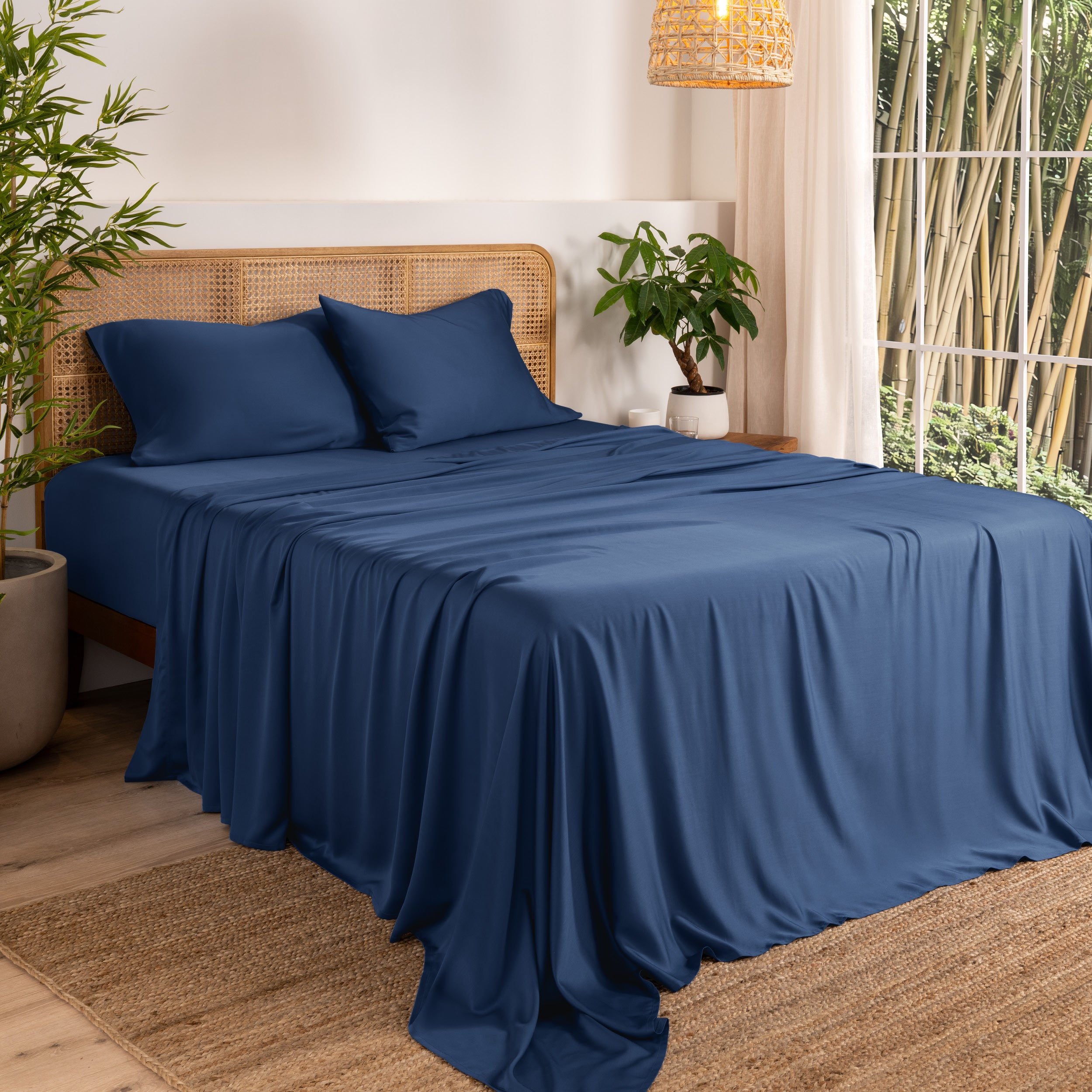 Bamboo sheets on a bed in a bedroom with plants and a window.