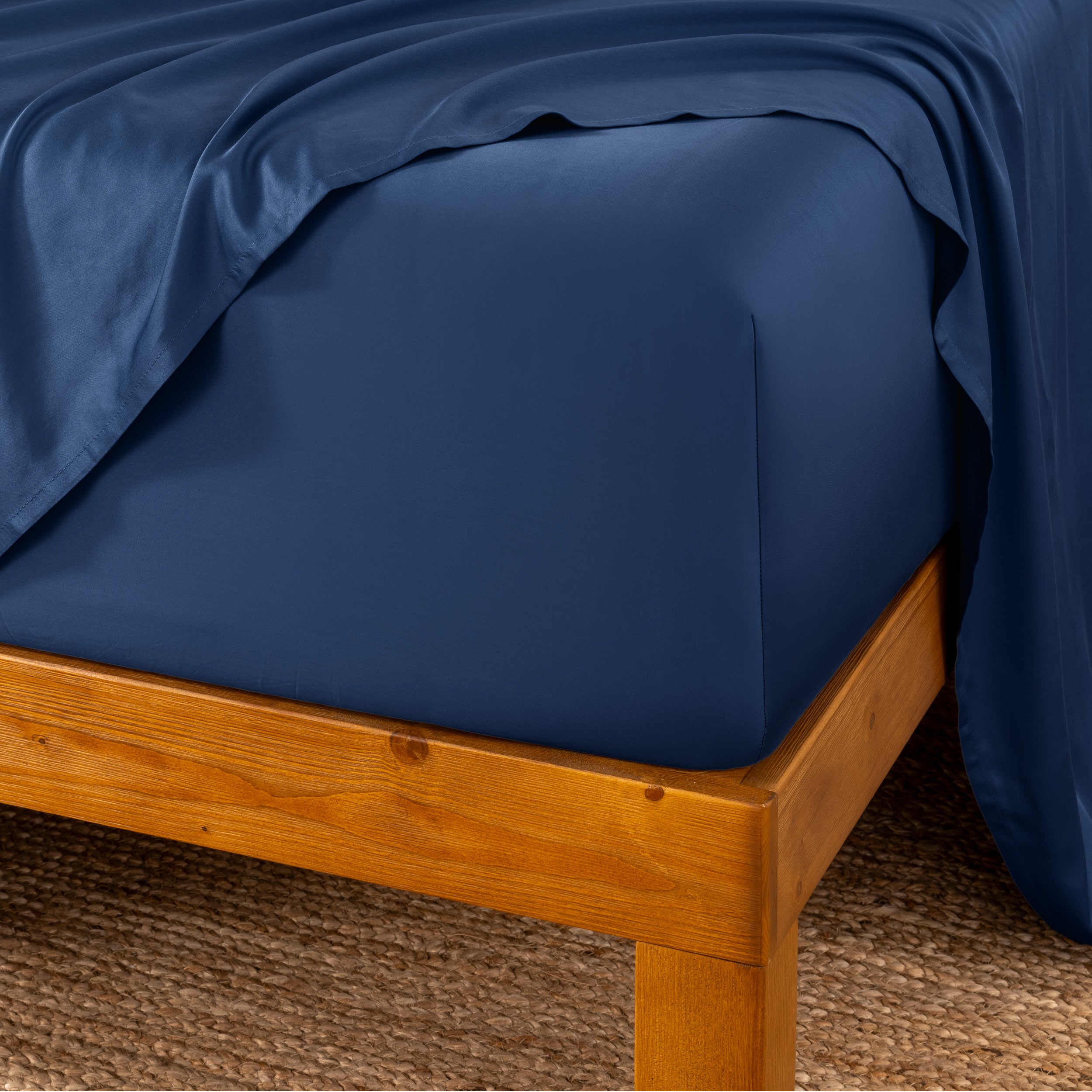 Bed sheets on a wooden bed frame with a brown carpet background