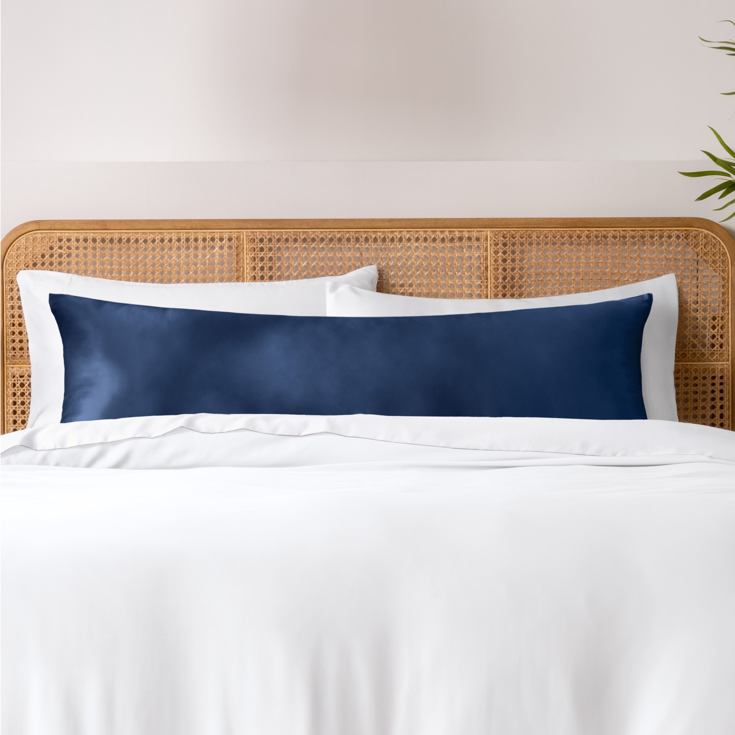 Bamboo body pillowcase on a bed with white bedding and a wicker headboard.