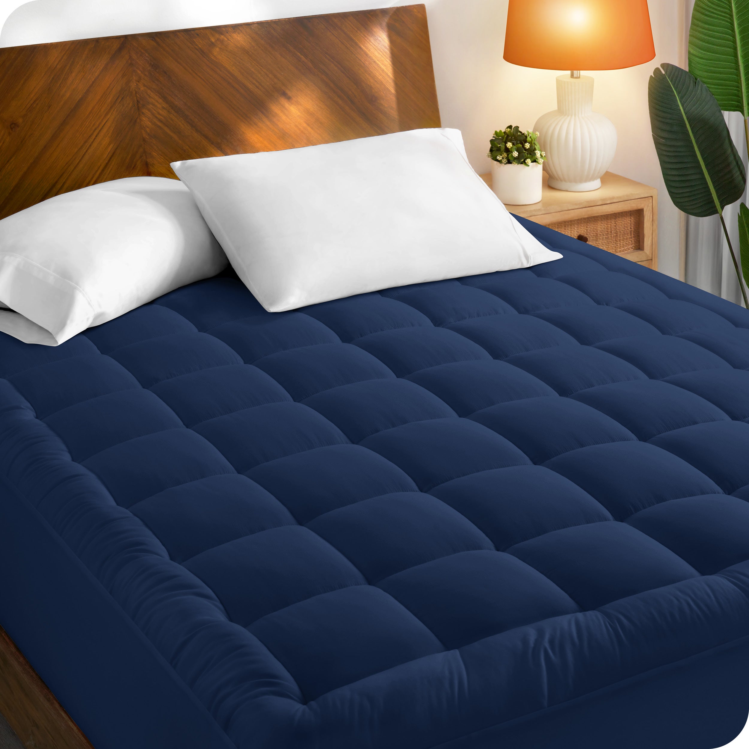 A mattress pad on a bed with a wooden headboard
