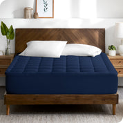 A modern bedroom with plants on the nightstands and a mattress pad on the bed