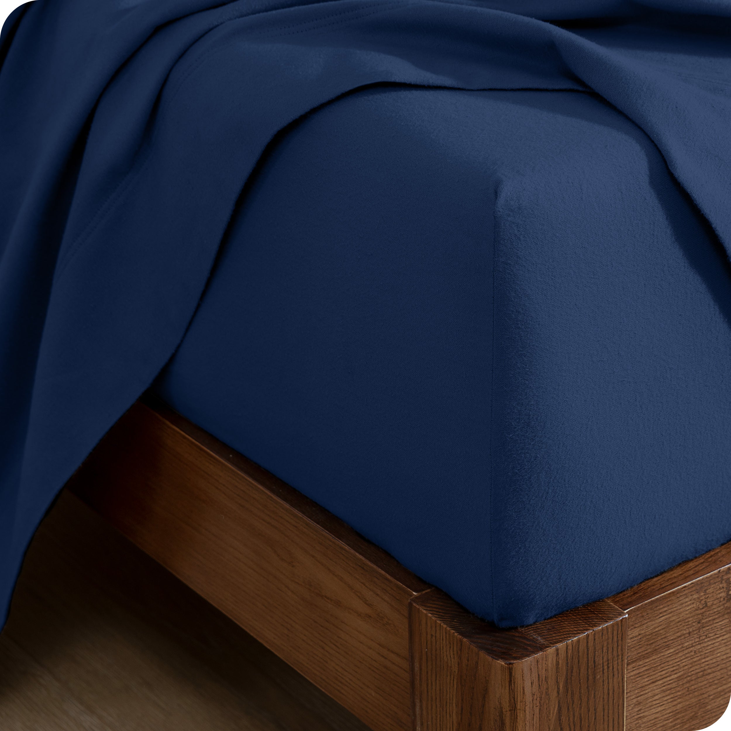 Close up of the corner of a mattress with a fitted sheet and flat sheet on it