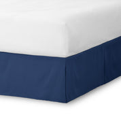 The corner of a bed skirt on a bed frame