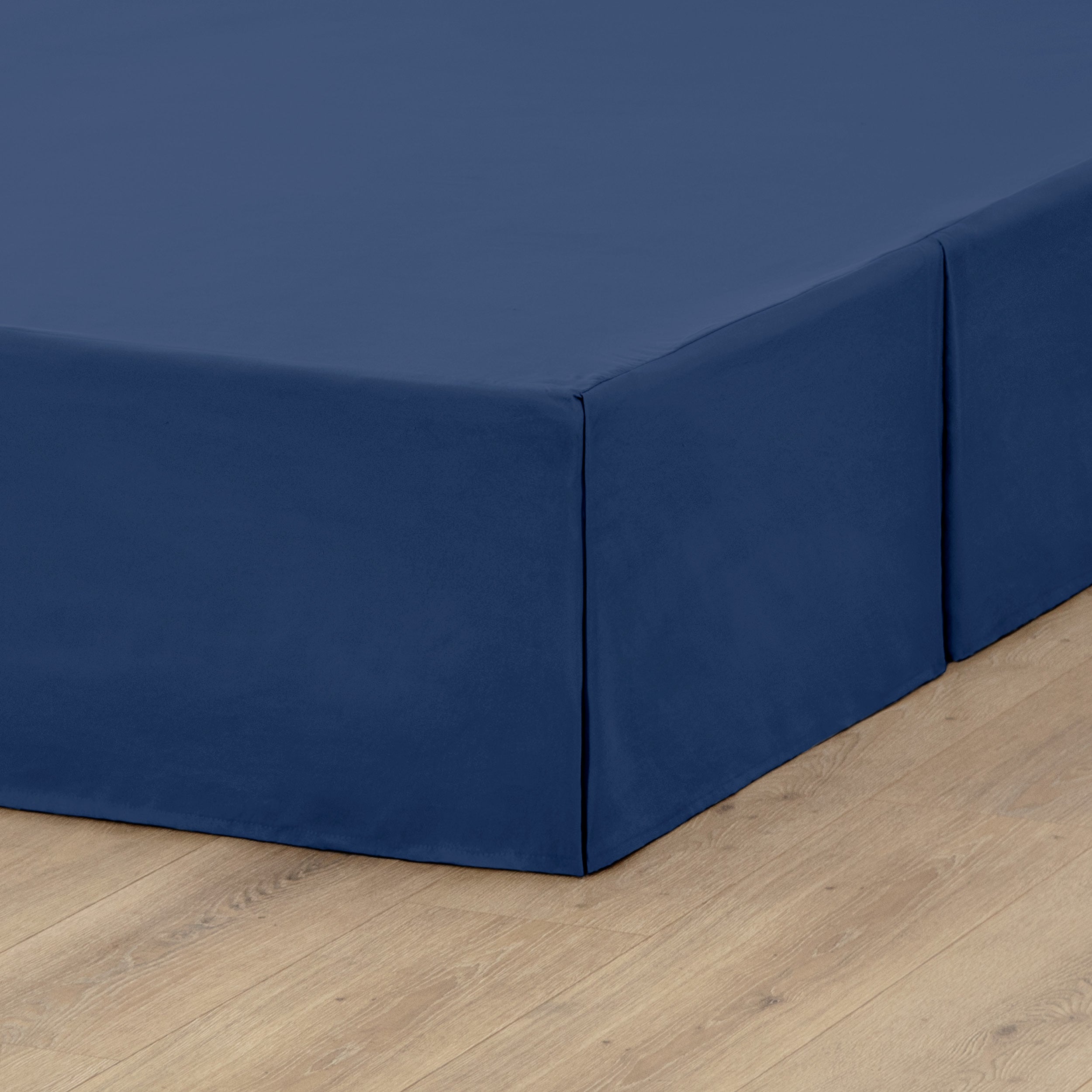 A box spring with a bed skirt on it