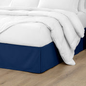 The corner of a bed with a bed skirt and comforter on it