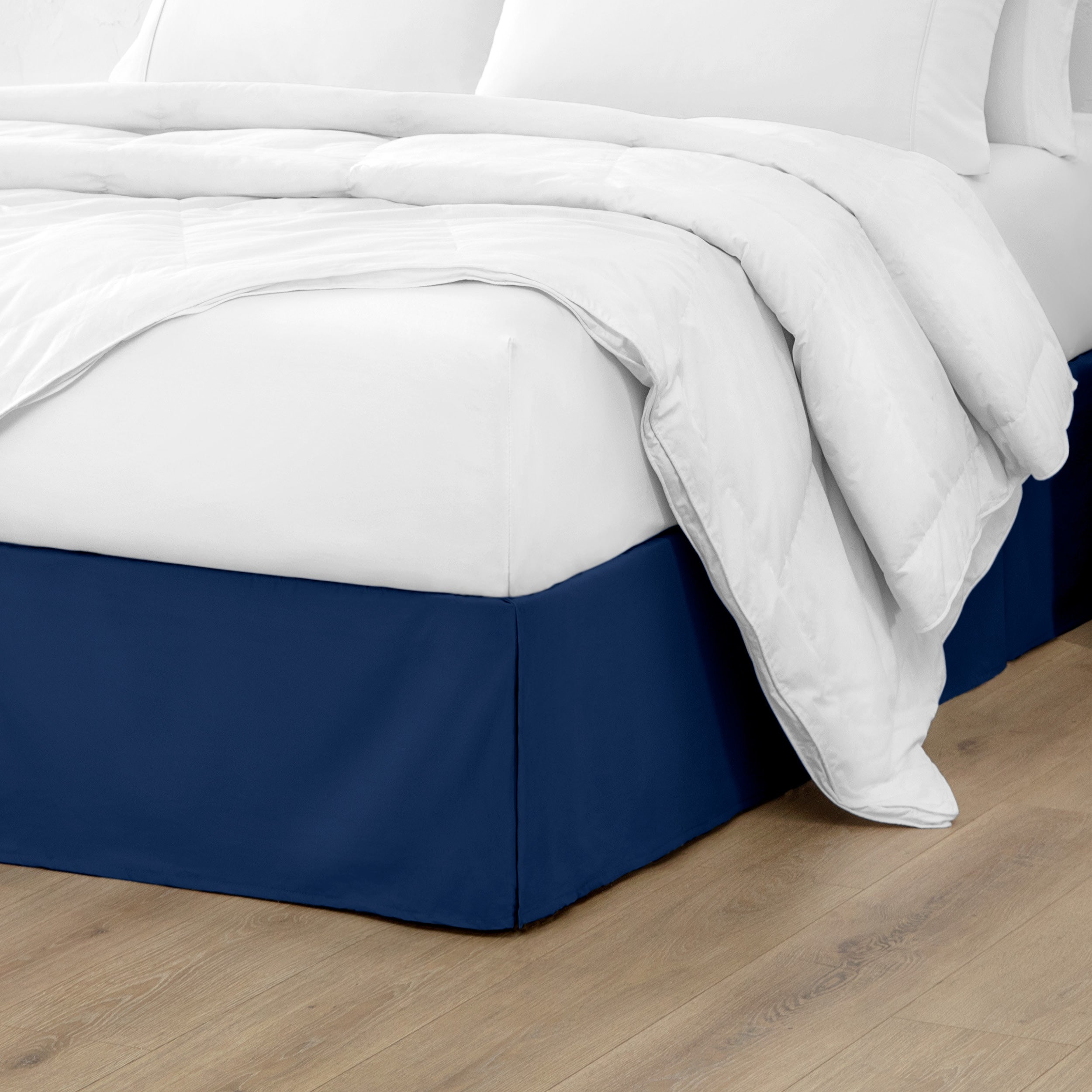 The corner of a bed with a bed skirt and comforter on it