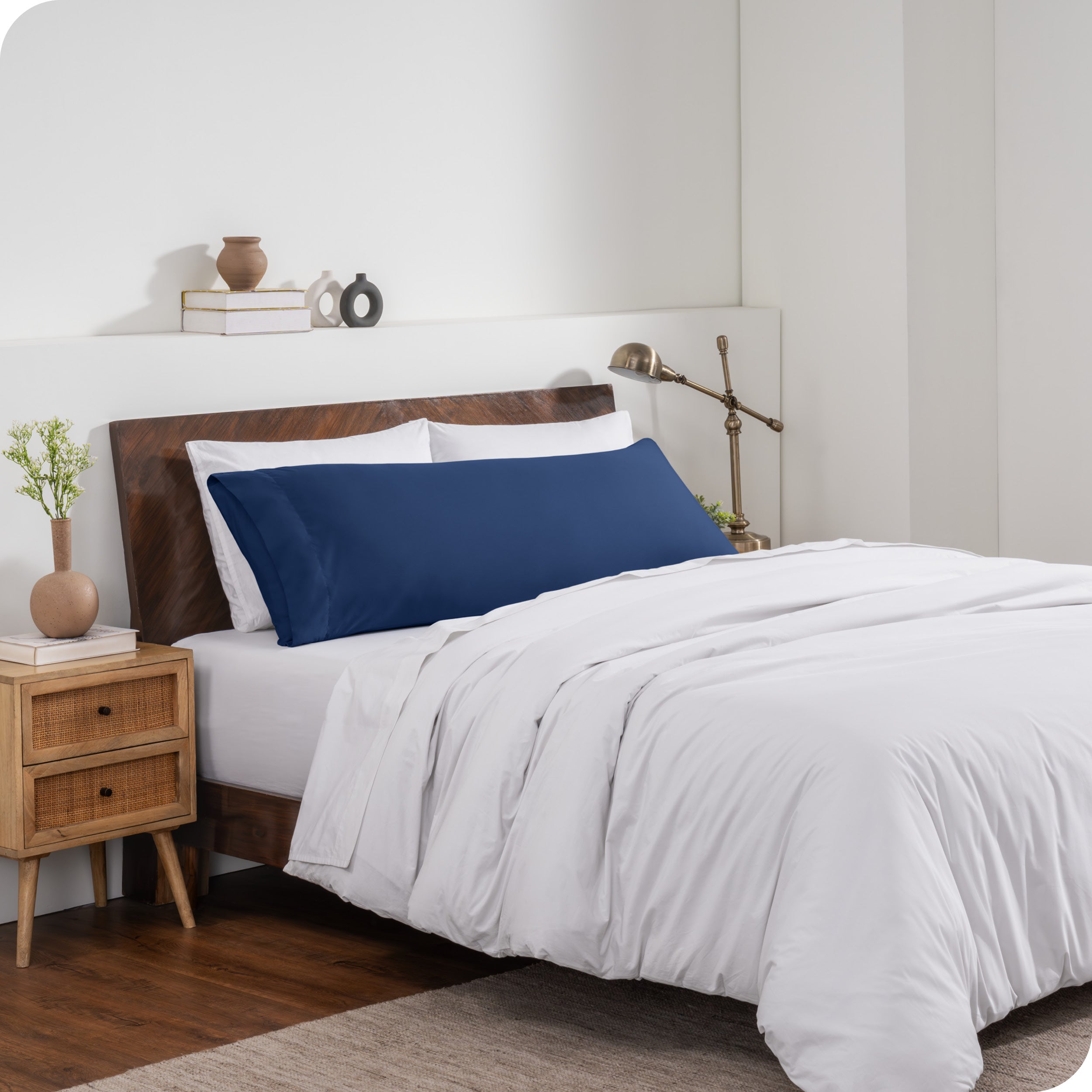 A body pillow cover on a pillow on a bed made with all white bedding