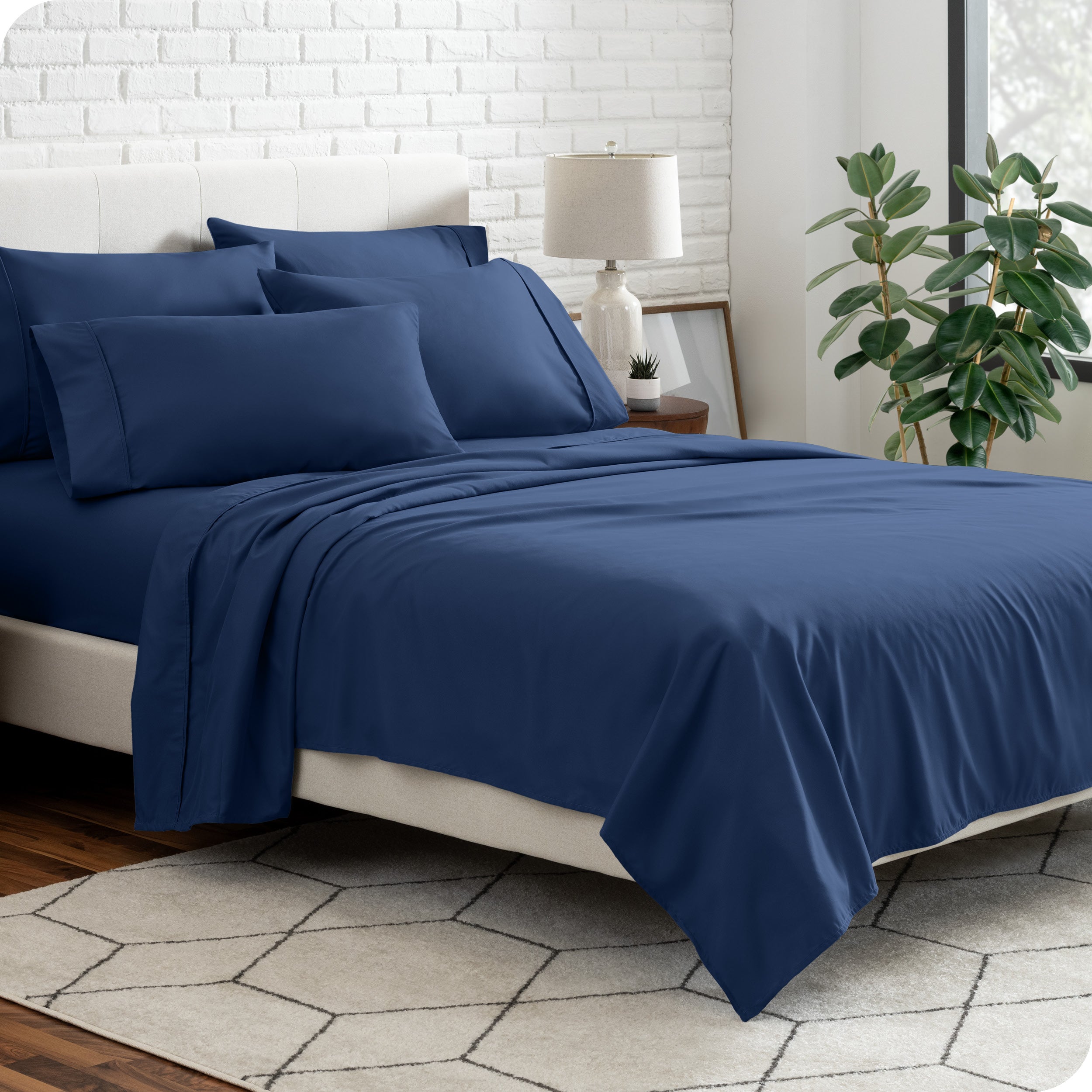 A bedroom setting with a bed made with the microfiber bed sheets and four pillows.