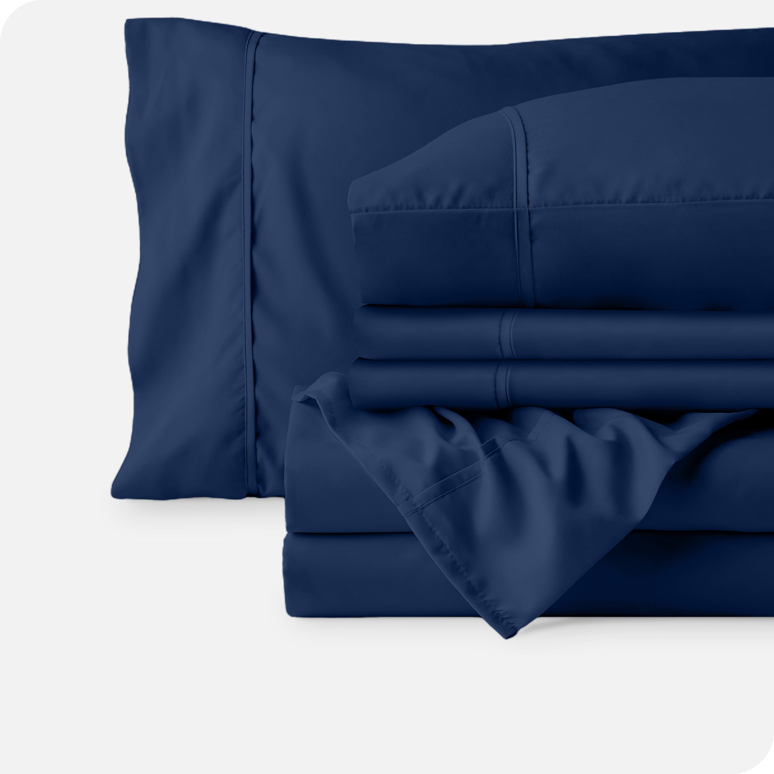 Microfiber sheets neatly folded with corner draped over, two folded pillowcases and two display pillows.