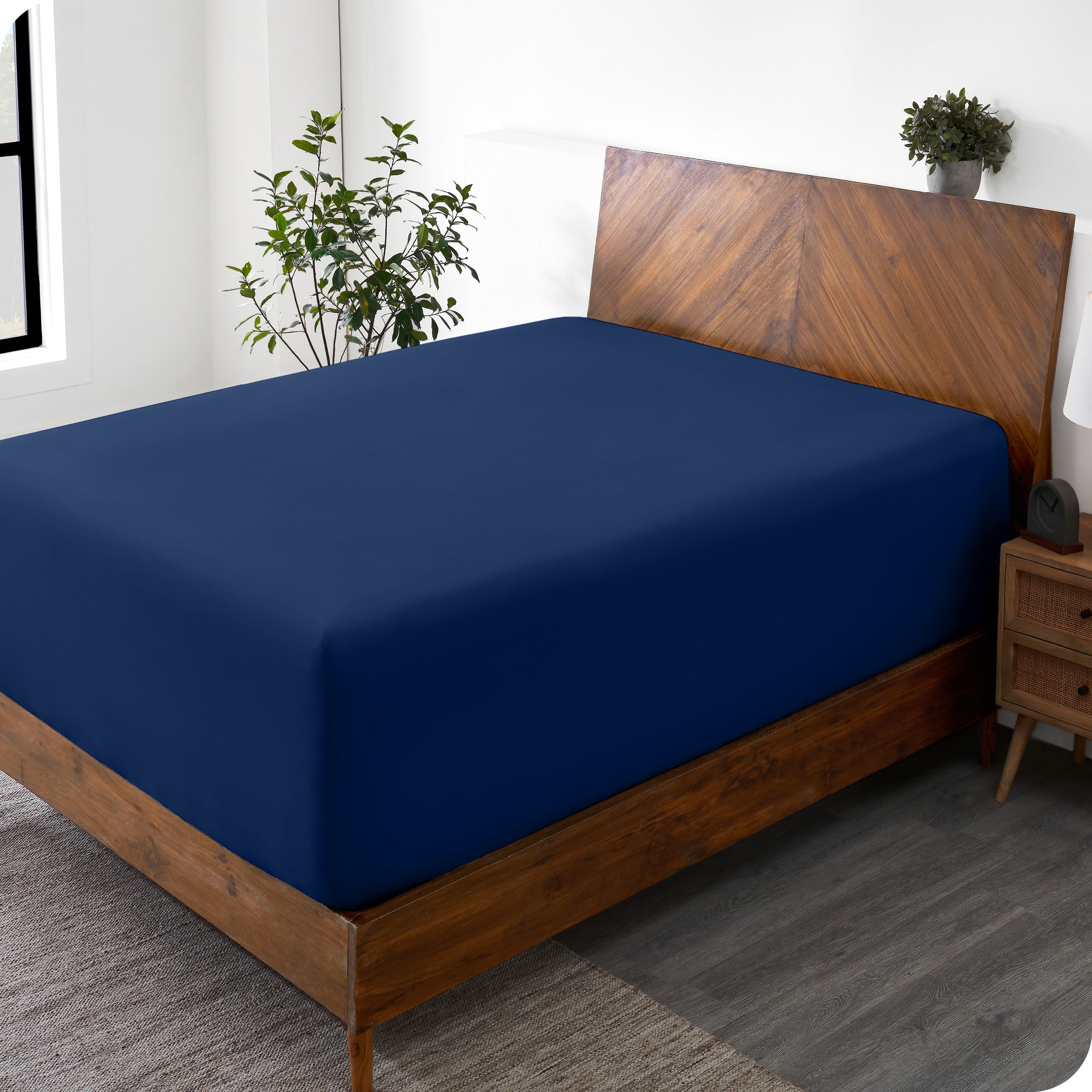 A wide corner view of a modern bed made with a microfiber fitted sheet on the mattress. 