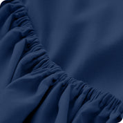 A close up of the elastic of a microfiber fitted sheet. 