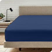 A bed with a microfiber fitted sheet on the mattress. 
